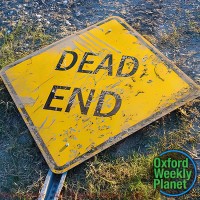 Dead End street sign lying on the ground with the Oxford Weekly Planet logo in the foreground
