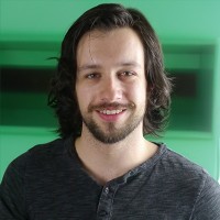 Smiling man with long dark hair and facial hair