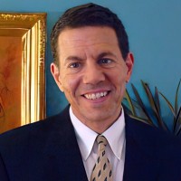 Smiling man with short dark hair and wearing a suit and tie