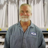 Smiling gray-haired and bearded man wearing coveralls