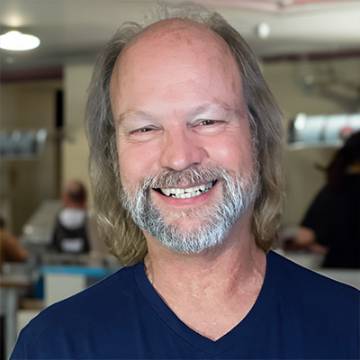 Smiling balding man with glasses and gray facial hair