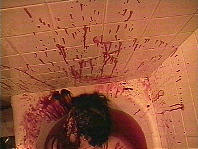 Bathtub filled with blood. Walls covered in spatter. Male victim floating in bloody water. View 1