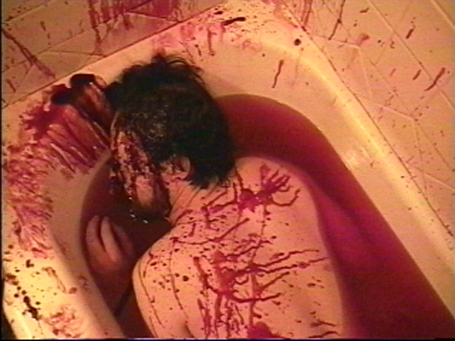 Bathtub filled with blood. Walls covered in spatter. Male victim floating in bloody water. View 3