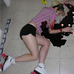 Young woman wearing roller skates, lying on the floor in a pool of blood