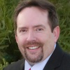 Smiling man with brown hair, mustache and goatee