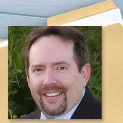 File folder with a photo of a smiling man with brown hair, mustache and goatee