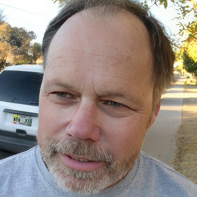 Balding man man with dark hair and salt-and-pepper facial hair