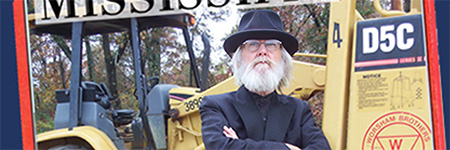 Man in front of ground moving machinery