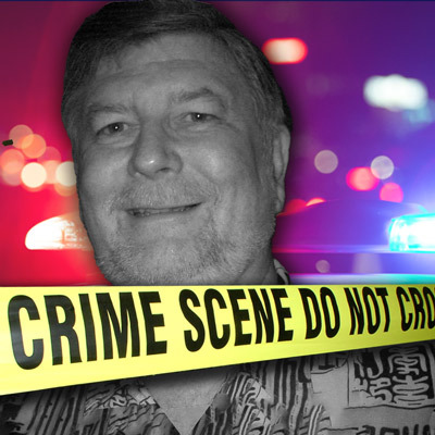 Smiling man with gray hair and facial hair with police lights in the background and crime scene tape in the foreground