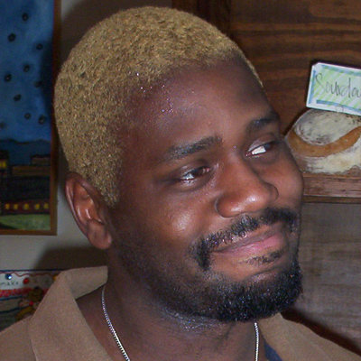 Smiling man with bleached blond hair and a dark goatee and mustache