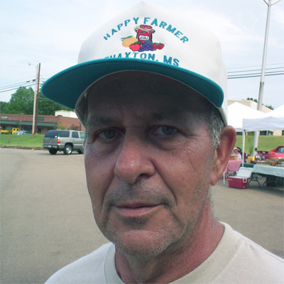 Man with salt-and-pepper hair and five o'clock shadow, wearing a t-shirt and trucker hat