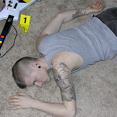 Young man with a mohawk slumped in a chair with a guitar video game controller in his lap