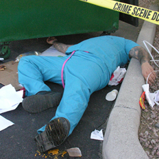 Man lying on his back next to a dumpster