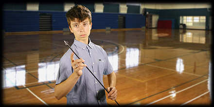 Teen boy holding an arrow, standing on an empty basketball court