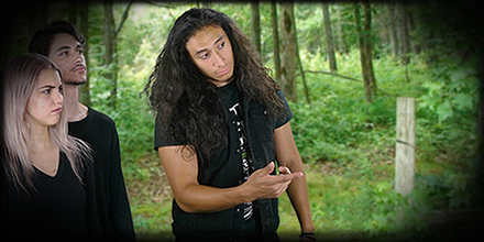 Two teen boys and a teen girl in the woods, pointing at something