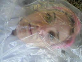 Pink-haired young woman wrapped in clear plastic