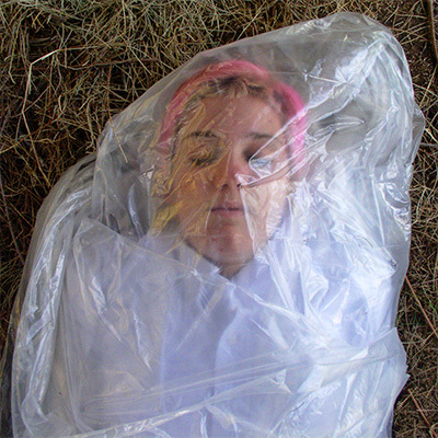 Pink-haired young woman wrapped in clear plastic