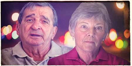 An older man with dark, graying hair and an unsmiling older woman with dark, graying hair