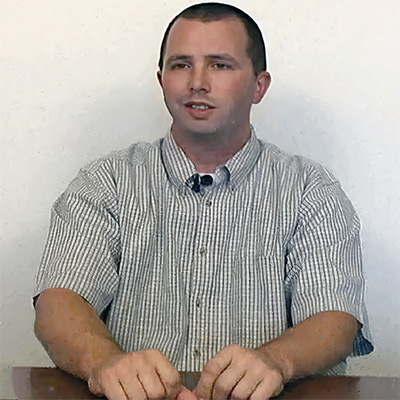 Unsmiling young man with very short dark hair