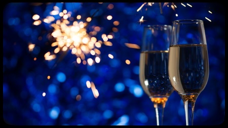 Glasses of champagne on a festive blue decoration with fireworks