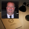 Smiling man with thinning hair in the foreground with a YCSD file folder on a desk in the background