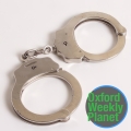 Handcuffs with the Oxford Weekly Planet logo in the foreground