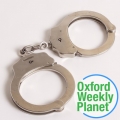 Handcuffs with the Oxford Weekly Planet logo in the foreground