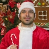 Man with dark hair and scruffy facial hair wearing a Santa suit