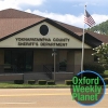 Exterior of the Yoknapatawpha County Sheriff's Dept. office with the Oxford Weekly Planet logo superimposed in the lower right corner