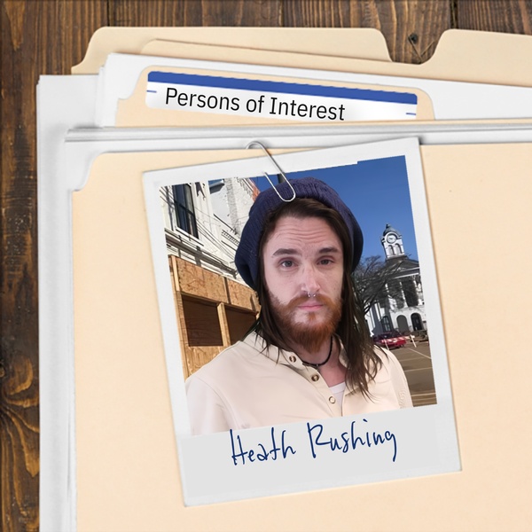 Manila folder with a photo of a young man with long dark hair and scruffy beard clipped to it