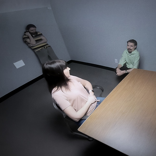 Surveillance image of two men and a woman in an interview room