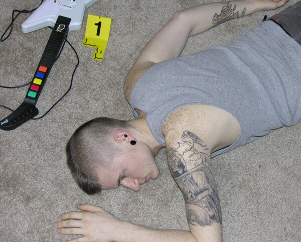 alt="Young man with a mohawk slumped in a chair with a guitar video game controller in his lap"