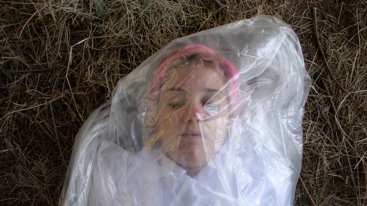 A woman wrapped in plastic and seems to be dead. Her eyes are closed