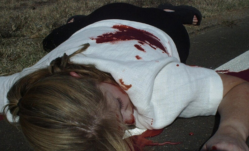 A woman in white on the ground covered in blood