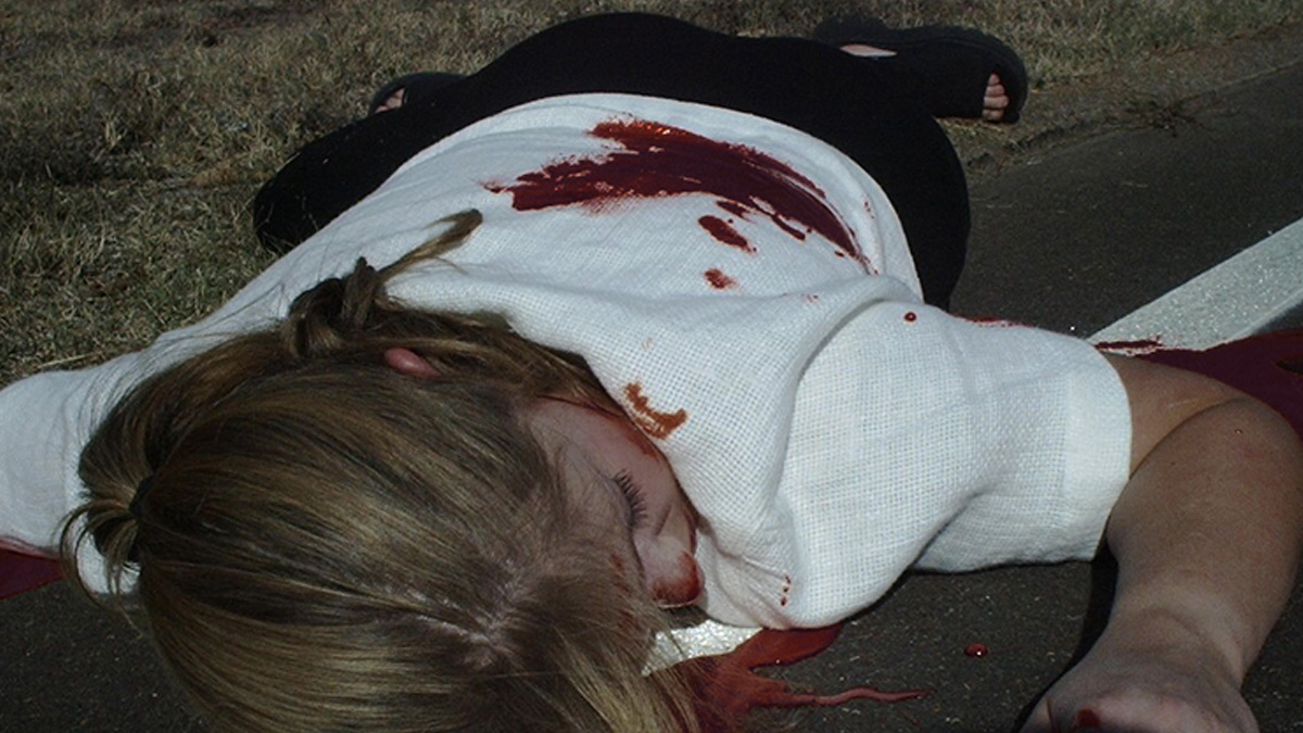 A woman in white on the ground covered in blood