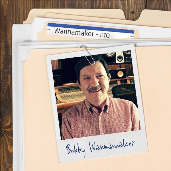 We see a file folder on a desk. Clipped to the folder is a picture of a man with a salt and pepper mustache and dark hairpiece