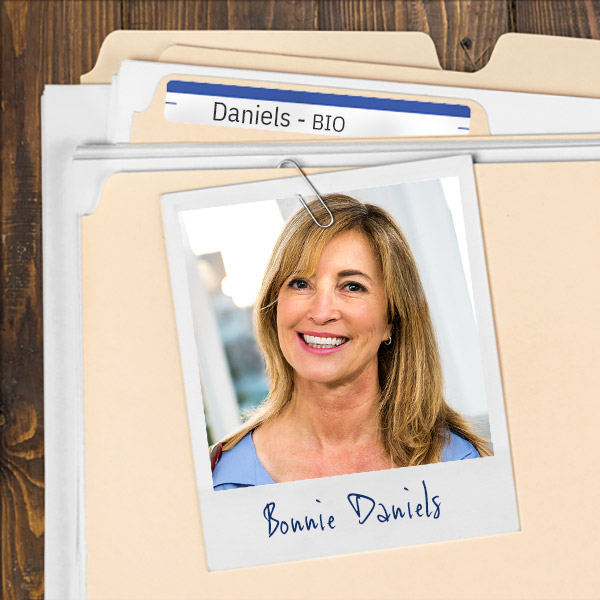 We see a file folder on a desk. Clipped to the folder is a picture of a smiling woman with blonde hair