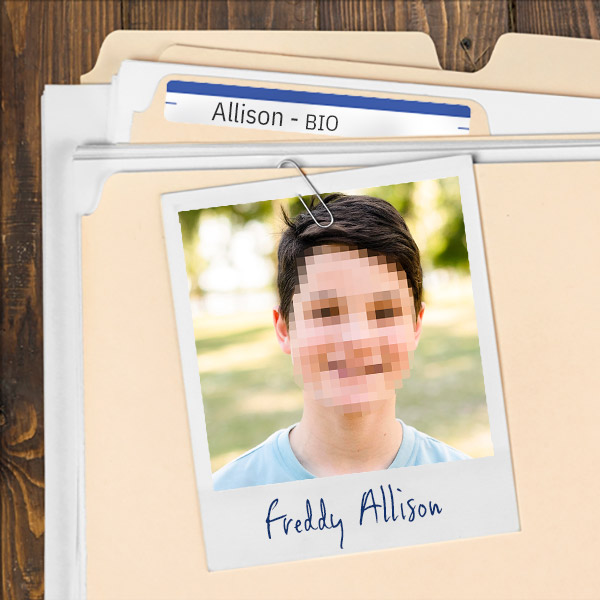 We see a file folder on a desk. Clipped to the folder is a picture of a pixelated photo of smiling tween boy