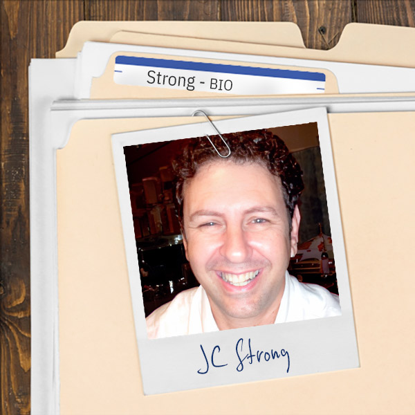 We see a file folder on a desk. Clipped to the folder is a picture of a Smiling man with short, dark curly hair