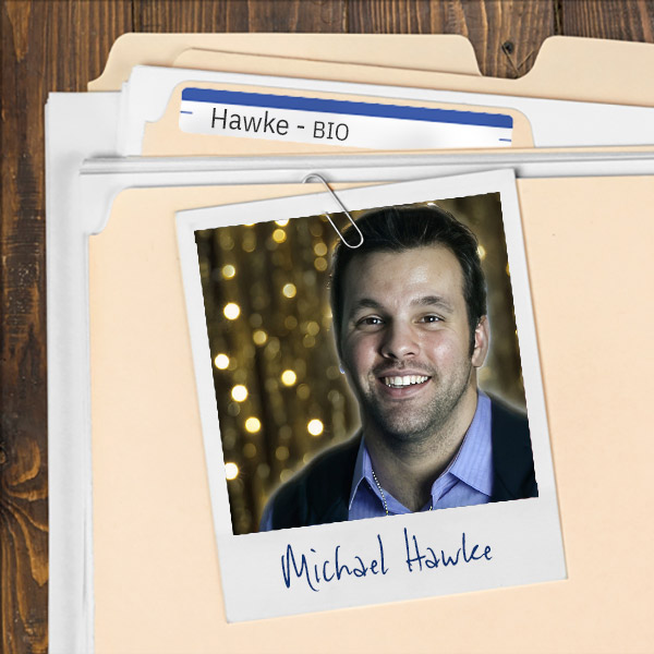 A file folder with a photo of a smiling man with dark hair and scruffy facial hair clipped to it.