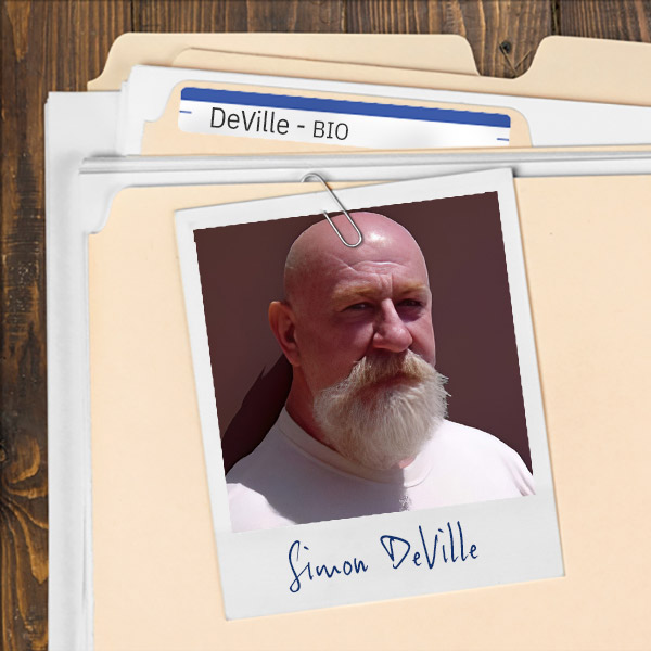 We see a file folder on a desk. Clipped to the folder is a picture of a bald man with bushy white mustache and goatee