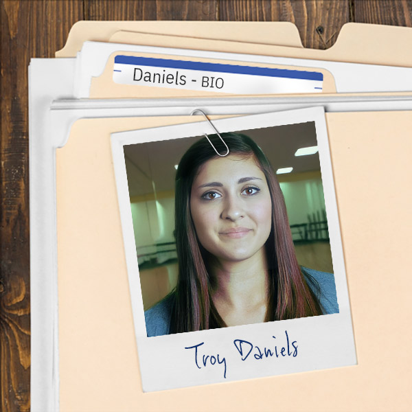 A file folder with a photo of a young woman with long dark hair clipped to it.