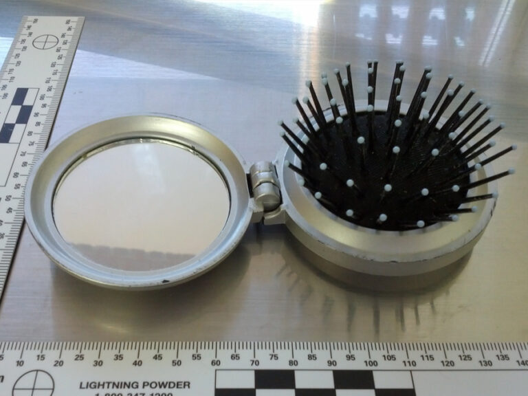 A picture of a folding hairbrush with a mirror inside it, recovered from a purse.