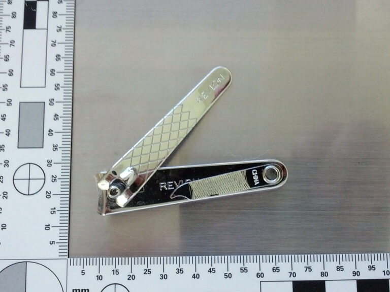 a picture of a silver nail clipper taken near a 90-degree measuring ruler
