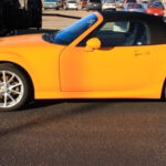 A yellow-colored car with 2 doors and a convertible hood