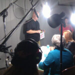 a group of people directing an actor with microphones, lights, and cameras.