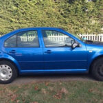 an older looking blue Volkswagen Jetta with a black tire.