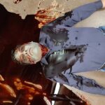 A picture of a pale body with blood pooling around him.