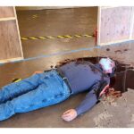 A wide shot picture of a pale body with blood pooling around him.