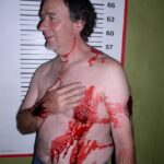 A picture of a shirtless man covered in blood